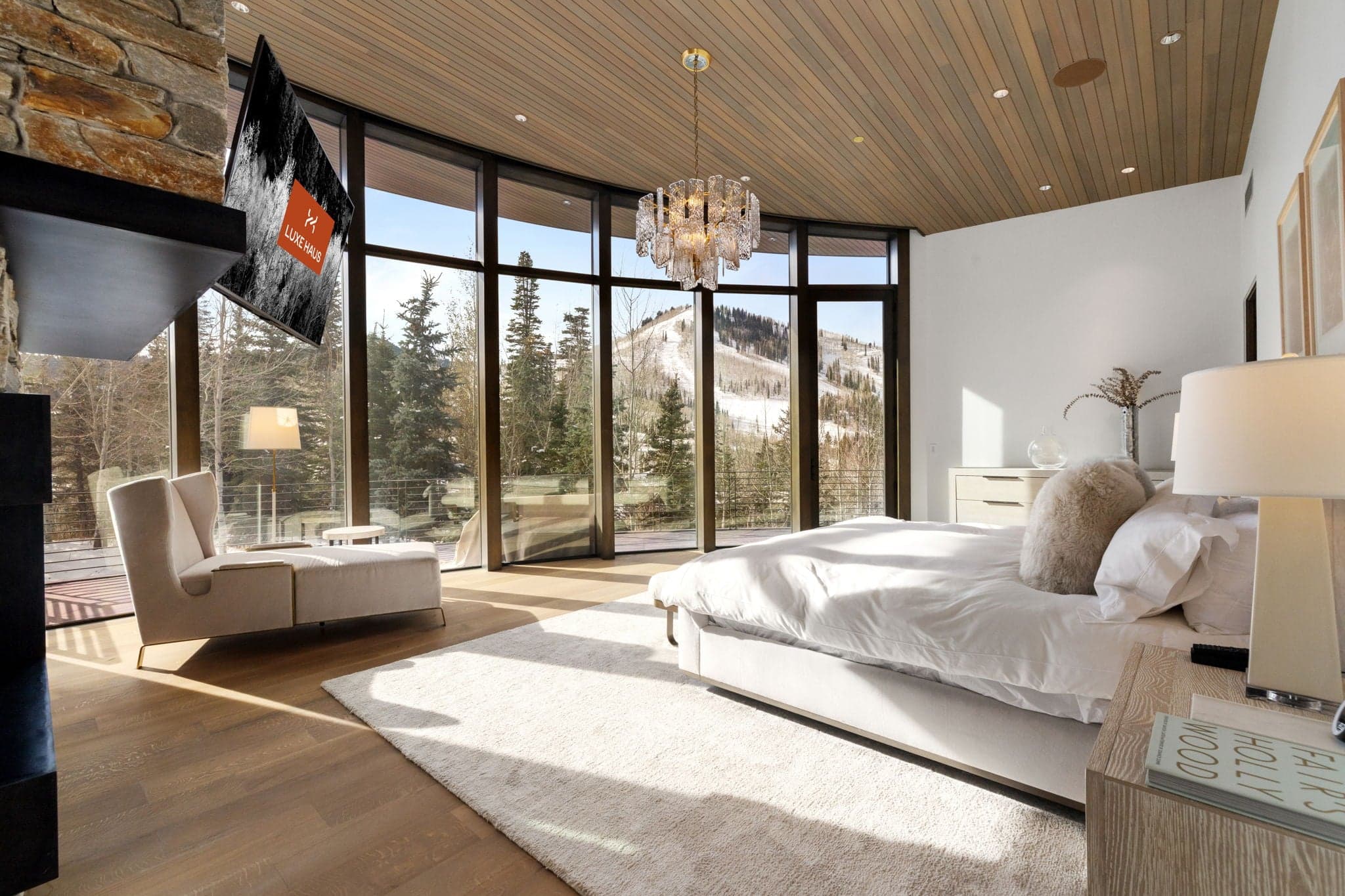 A bedroom with floor-to-ceiling windows and a flatscreen tv.