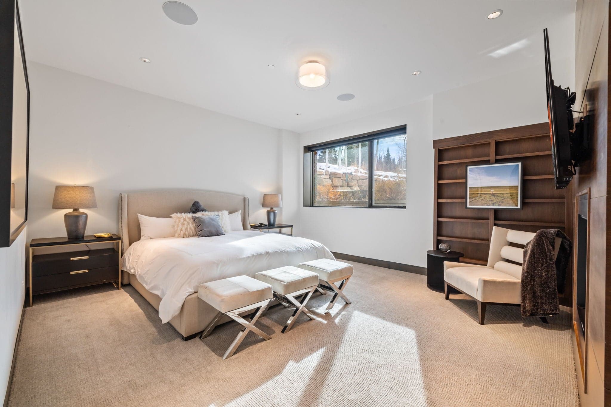 A bedroom with a bed, a side table, and book case.